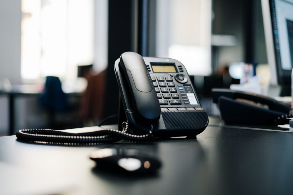 Black IP desk phone on a wooden table, representing the best business VoIP phone systems for 2026