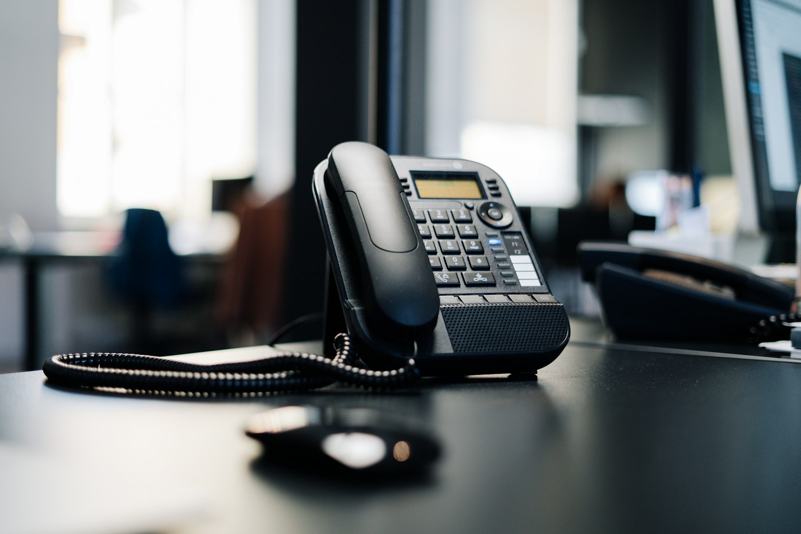 Black IP desk phone on a wooden table, representing the best business VoIP phone systems for 2026