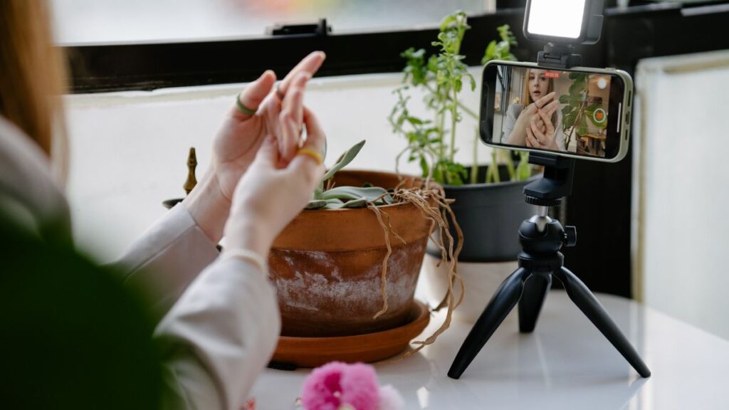 Woman using a smartphone on a tripod to record video content for editing with mobile video editing apps