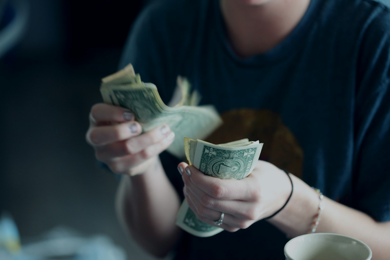 Person counting dollar banknotes, representing payroll processing handled by the best payroll software for small businesses in 2026