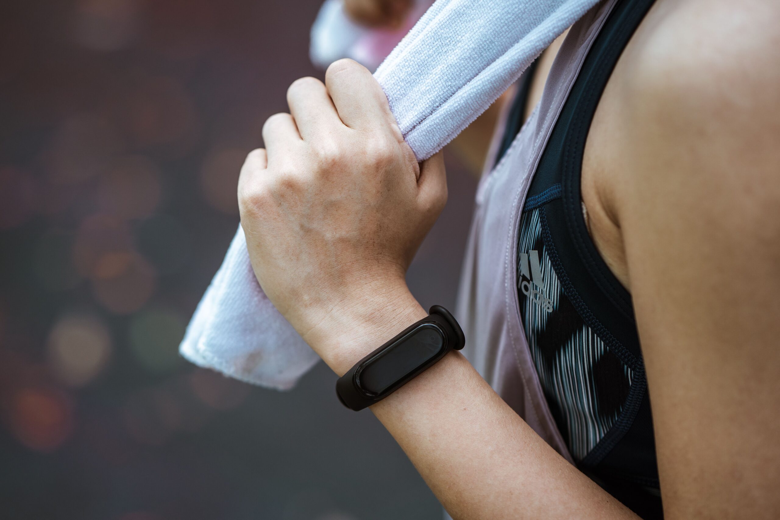 Woman checking a wrist fitness band while exercising outdoors, representing the Google Fitbit Air sleep and heart rate tracking features