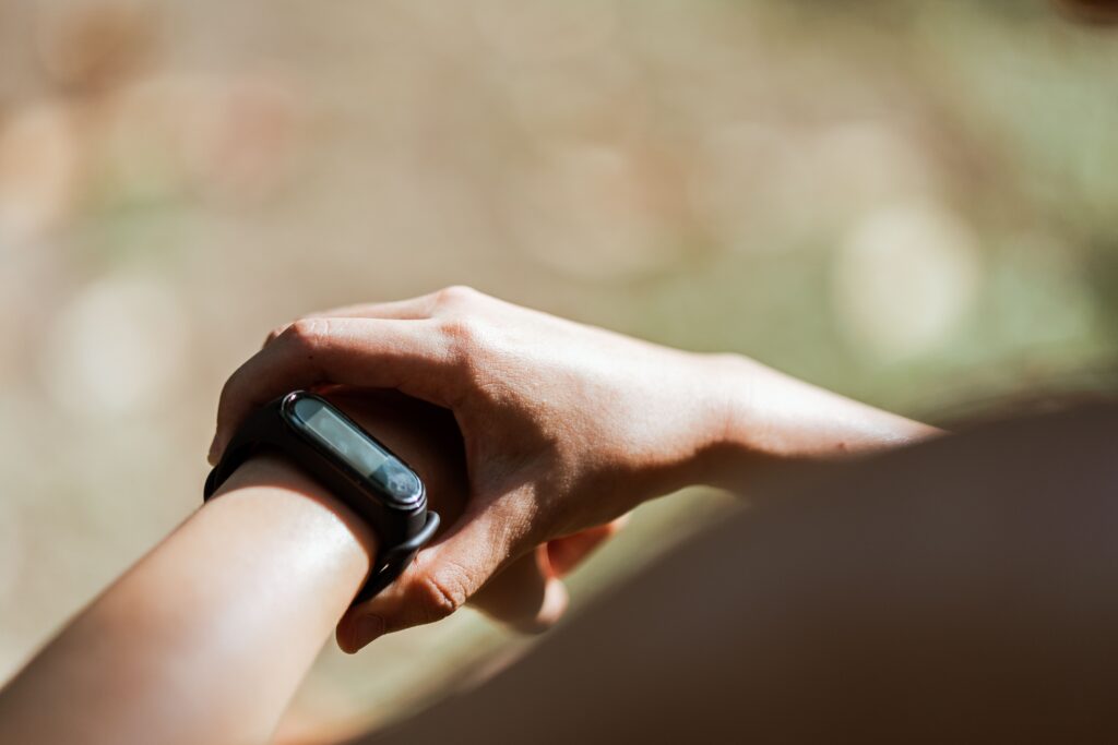 Close-up of a fitness tracker band on a wrist outdoors, representing the screenless Google Fitbit Air health tracker