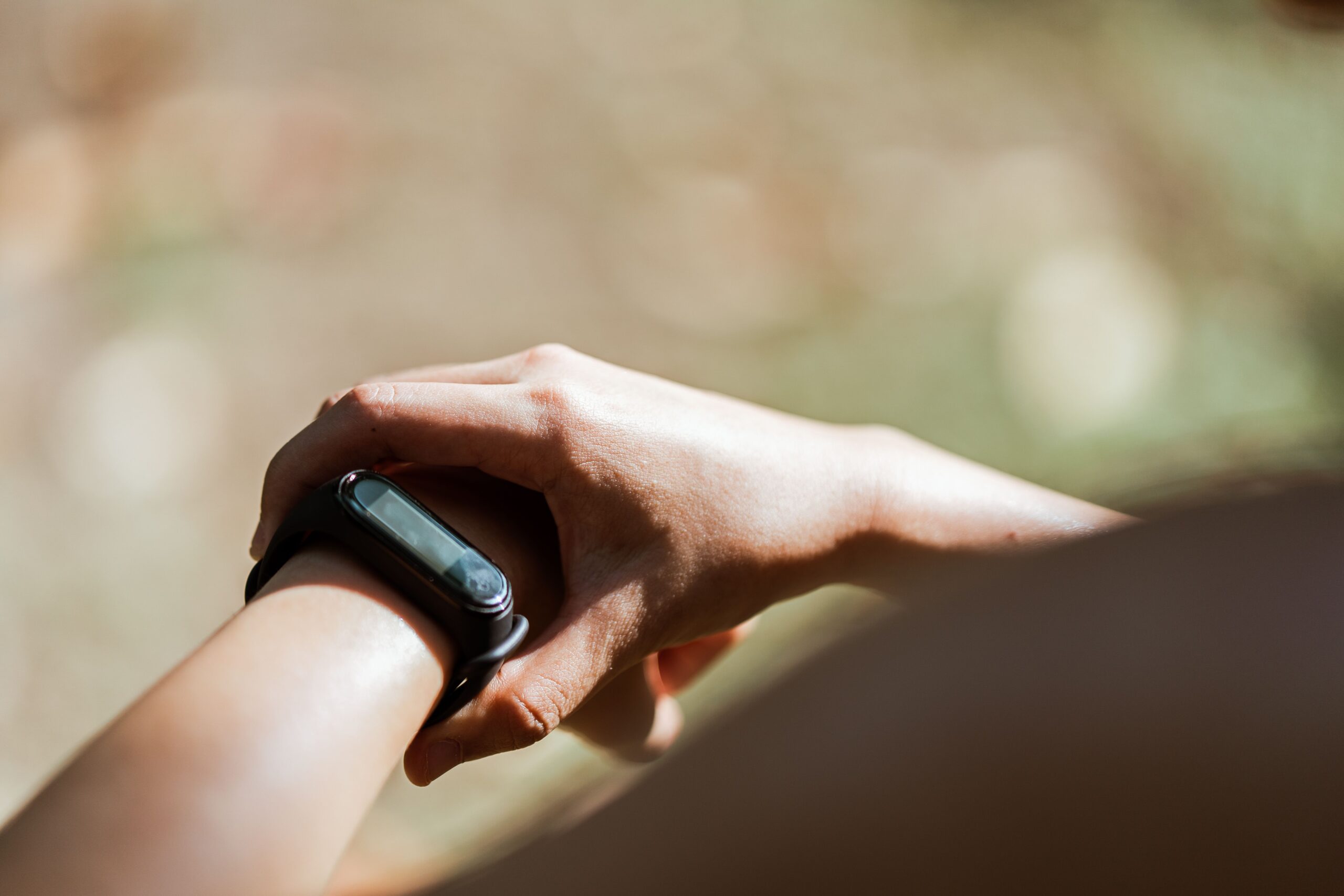 Close-up of a fitness tracker band on a wrist outdoors, representing the screenless Google Fitbit Air health tracker