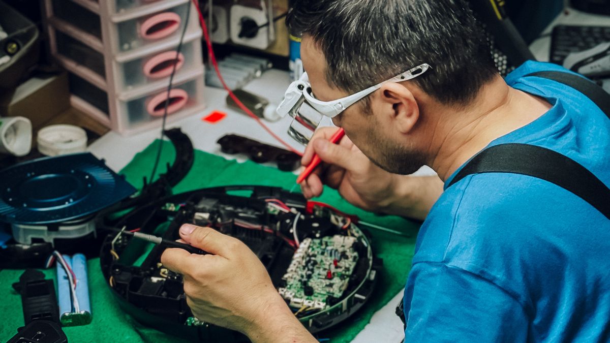 Technician repairing and upgrading laptop hardware components on a workbench