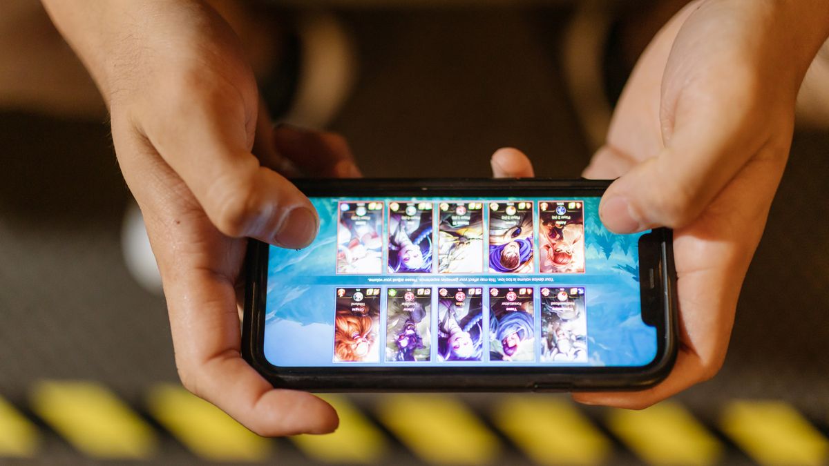 Close-up of hands playing a mobile battle royale game on a smartphone screen