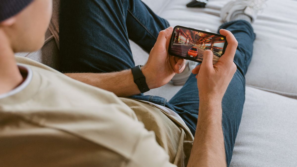 Close-up of hands holding a smartphone playing a mobile battle royale game with in-game HUD visible
