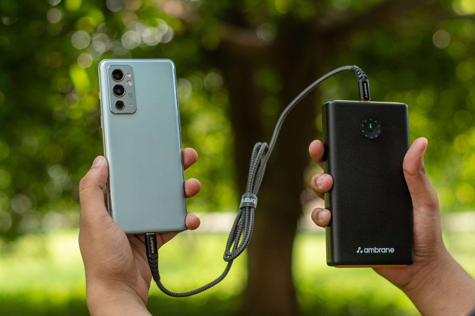 Hands holding a smartphone connected to a charging cable, representing the OPPO K15 Pro's large battery and fast charging