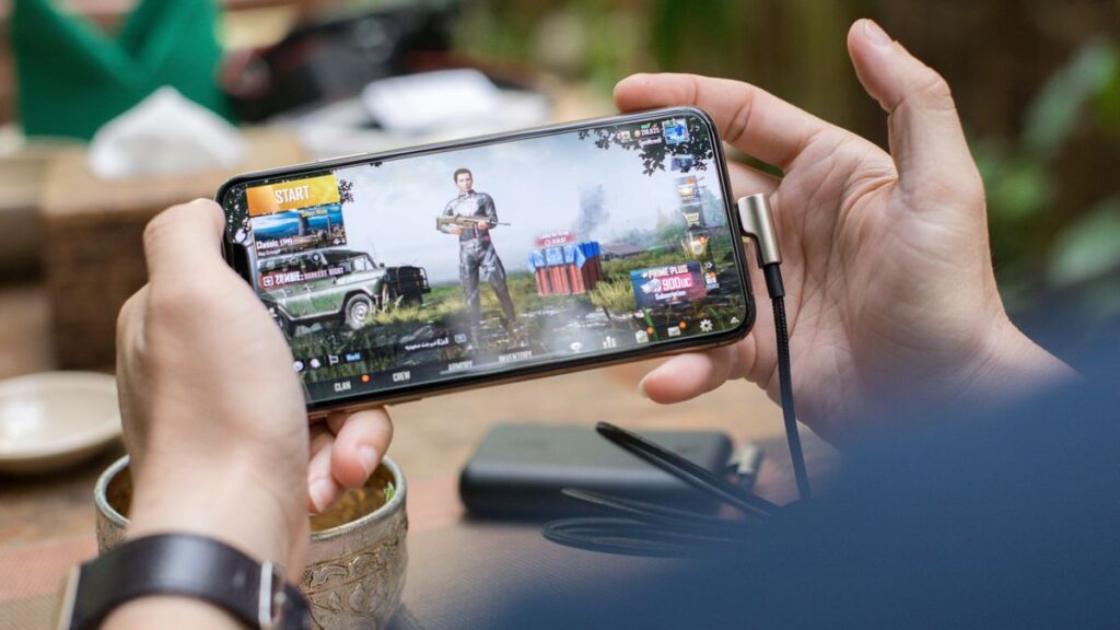 Person playing PUBG Mobile on a smartphone outdoors, representing the PUBG Mobile 4.6 update