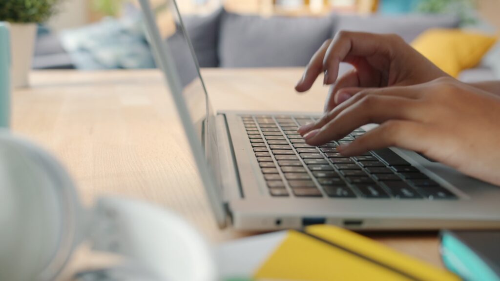 Hands typing on a laptop keyboard at a desk, representing the best AI writing tools 2026 like Grammarly and Jasper for editing and content creation