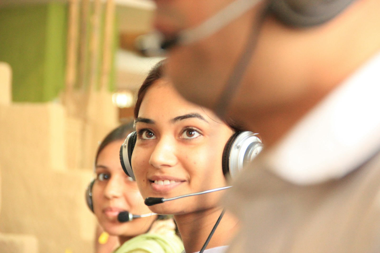 Two customer support agents wearing headsets in a bright office, illustrating teams using help desk software like Zendesk, Freshdesk, and Intercom in 2026