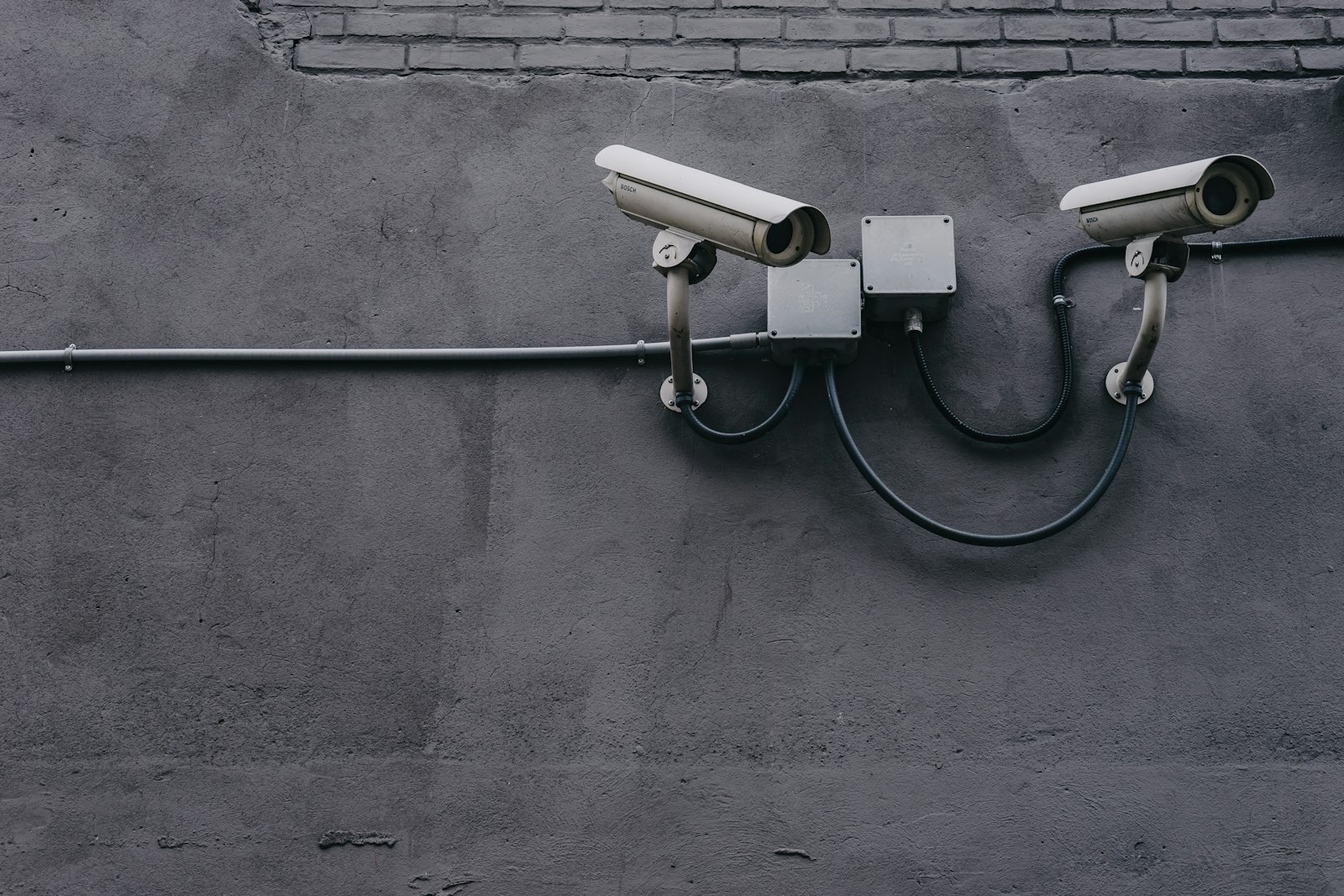Two outdoor surveillance cameras mounted on a wall, illustrating 24/7 professional monitoring used by the best home security system 2026 brands