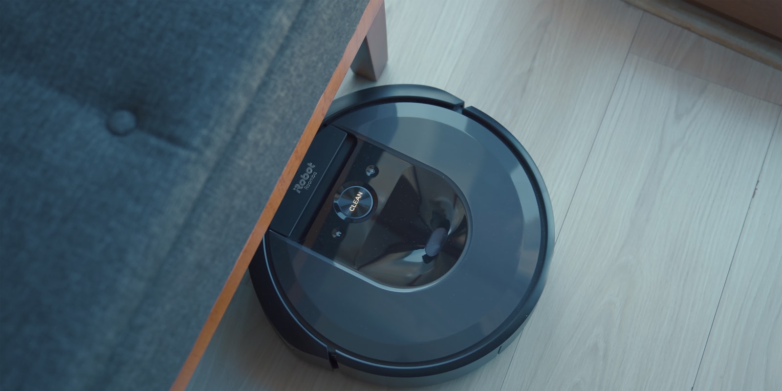 Robot vacuum cleaner sitting on the floor next to a couch, representing robot vacuums like Roborock, iRobot Roomba, and Ecovacs in the best robot vacuums 2026 comparison