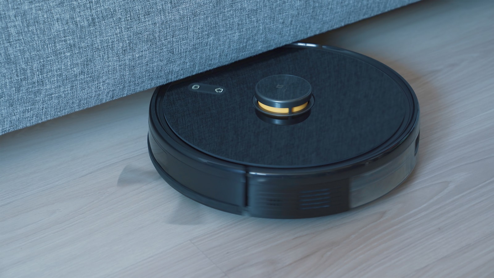 Black robot vacuum cleaning a wooden floor, illustrating the self-emptying docks and AI navigation compared in the best robot vacuums 2026 guide