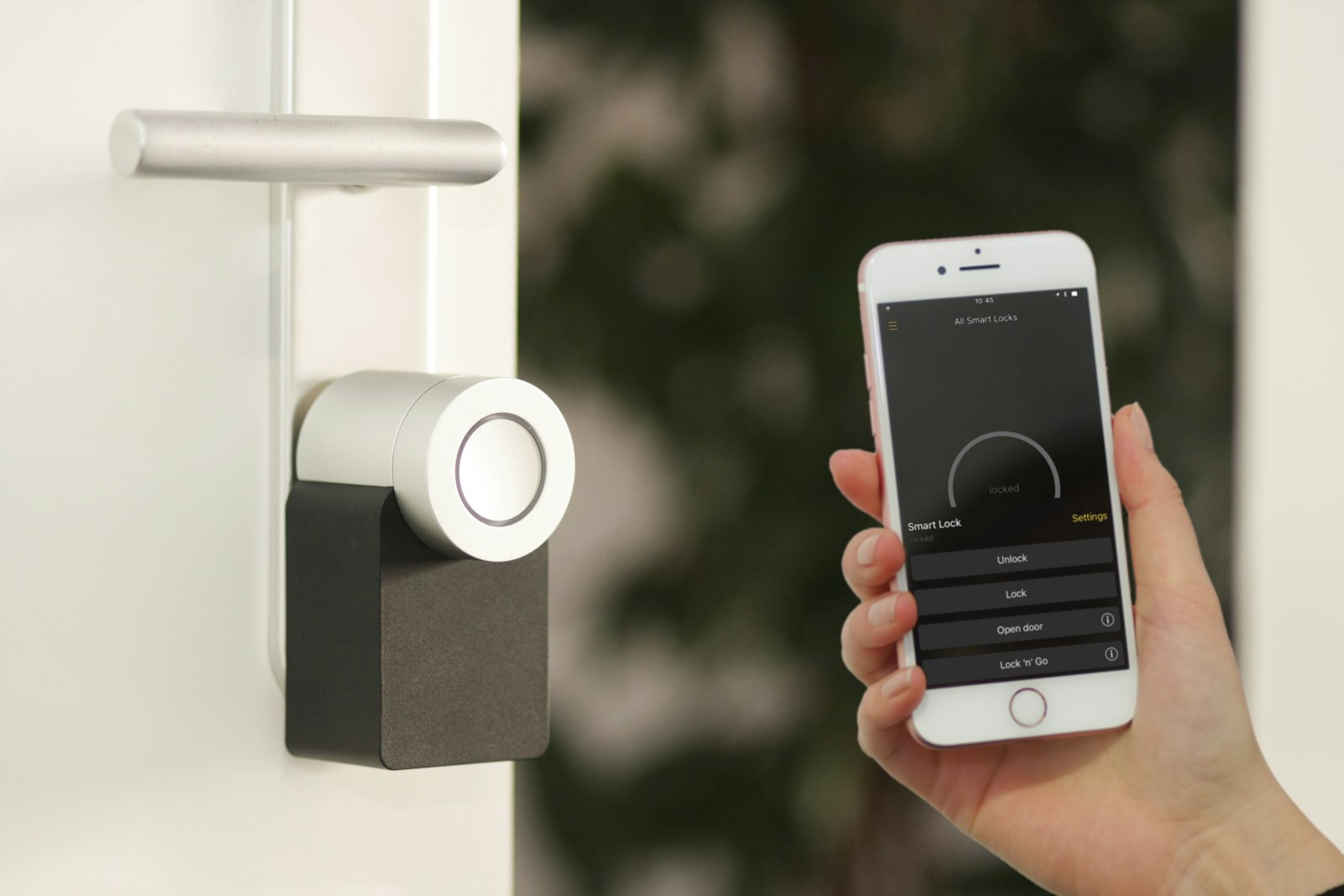 Smartphone held near a front door lock, representing app-controlled smart locks like August, Schlage, and Yale in the best smart locks 2026 comparison