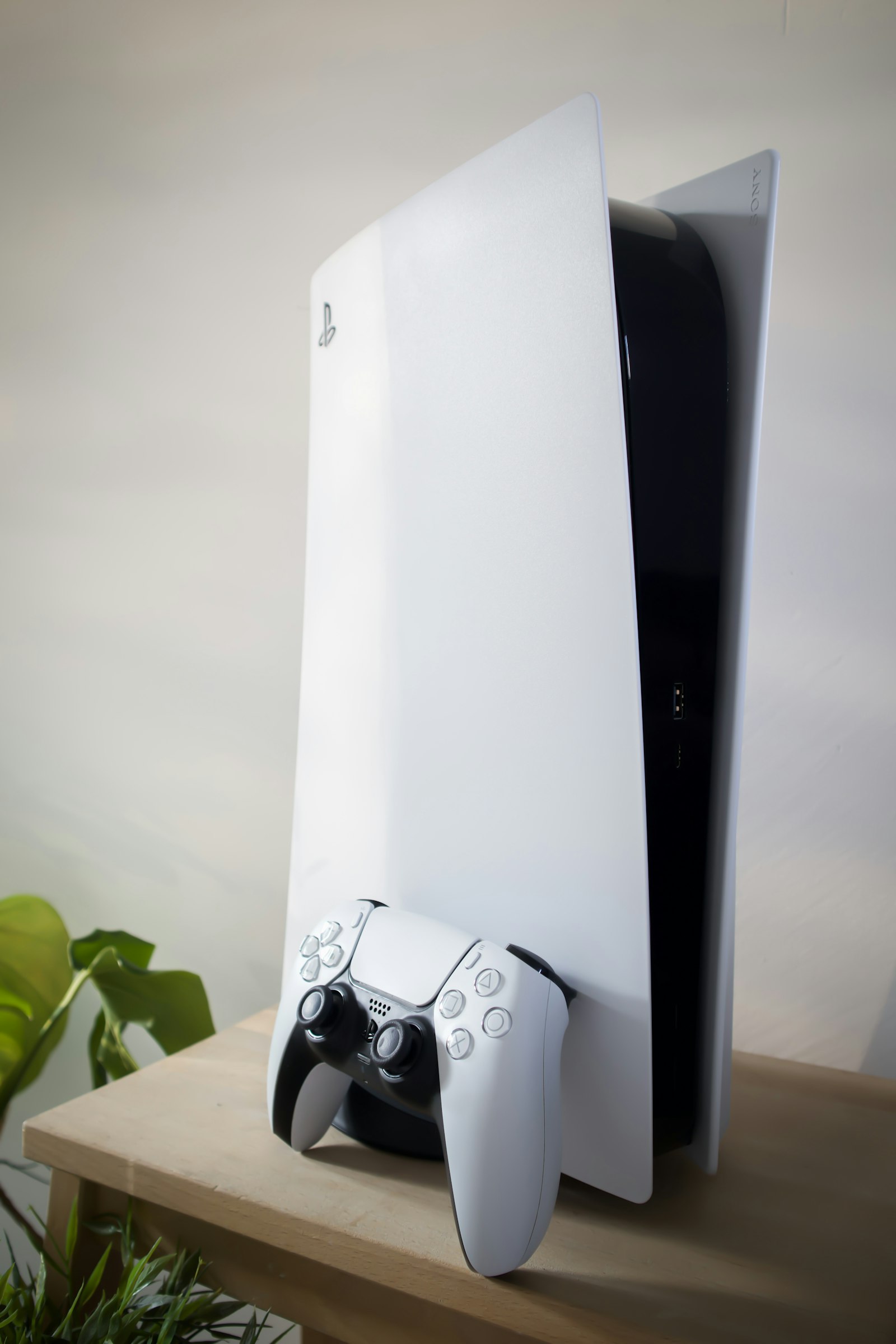Sony PlayStation 5 console with its DualSense controller on a wooden table, representing the $7.85 million PlayStation Store class action settlement over digital game pricing