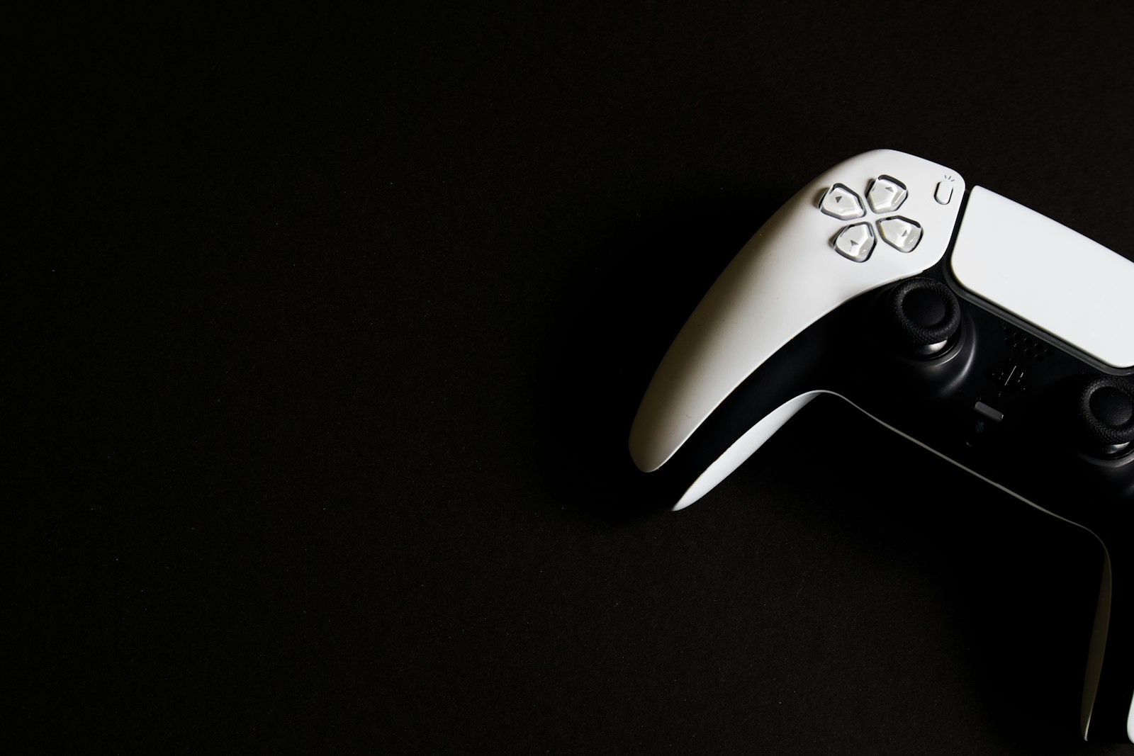 White PlayStation 5 controller on a black surface, illustrating the digital games covered by the Caccuri v. Sony Interactive Entertainment class action settlement
